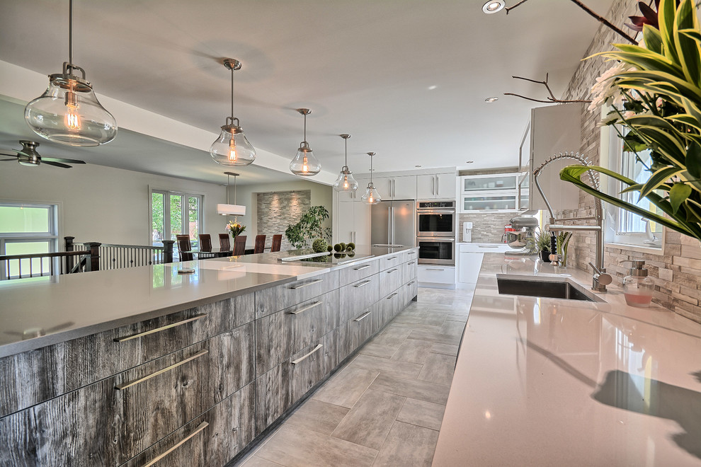 Expansive contemporary eat-in kitchen in Burlington with a single-bowl sink, solid surface benchtops, stainless steel appliances, with island, flat-panel cabinets, white cabinets, beige splashback and stone slab splashback.