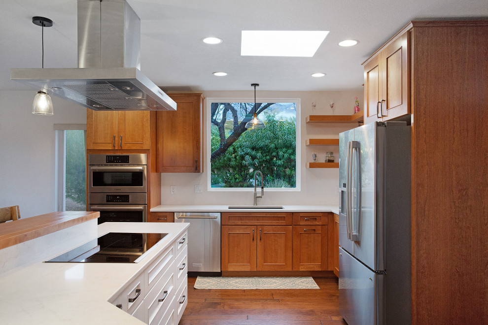 Mid-sized l-shaped dark wood floor and brown floor eat-in kitchen photo with an undermount sink, shaker cabinets, white cabinets, quartz countertops, stainless steel appliances, an island and white countertops