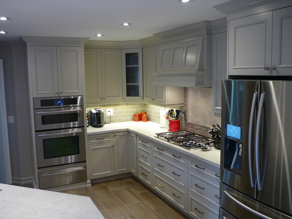 Inspiration for a mid-sized transitional l-shaped porcelain tile eat-in kitchen remodel in Toronto with an undermount sink, recessed-panel cabinets, porcelain backsplash, stainless steel appliances and a peninsula