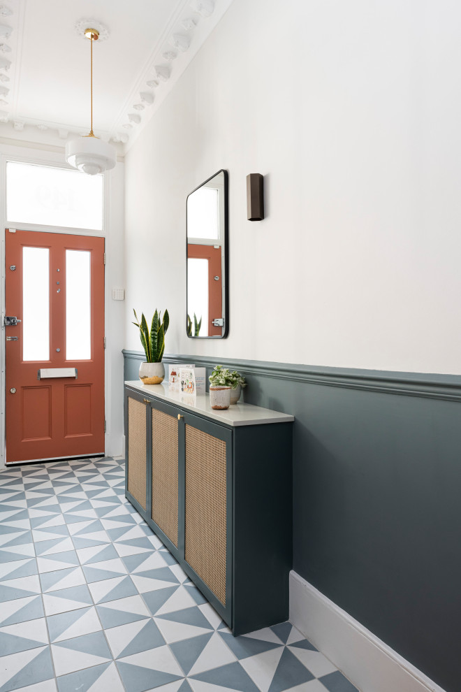 На фото: узкая прихожая среднего размера в викторианском стиле с синими стенами, полом из керамической плитки, одностворчатой входной дверью, красной входной дверью, синим полом, сводчатым потолком и панелями на части стены