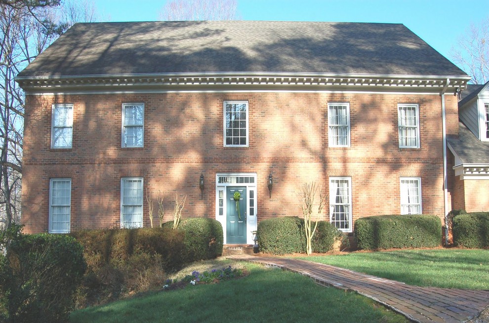 Large traditional two-storey brick red house exterior in Atlanta with a clipped gable roof and a shingle roof.