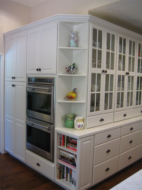 Example of a mid-sized transitional u-shaped dark wood floor and brown floor enclosed kitchen design in Orange County with an undermount sink, raised-panel cabinets, white cabinets, solid surface countertops, white backsplash, subway tile backsplash, stainless steel appliances and an island