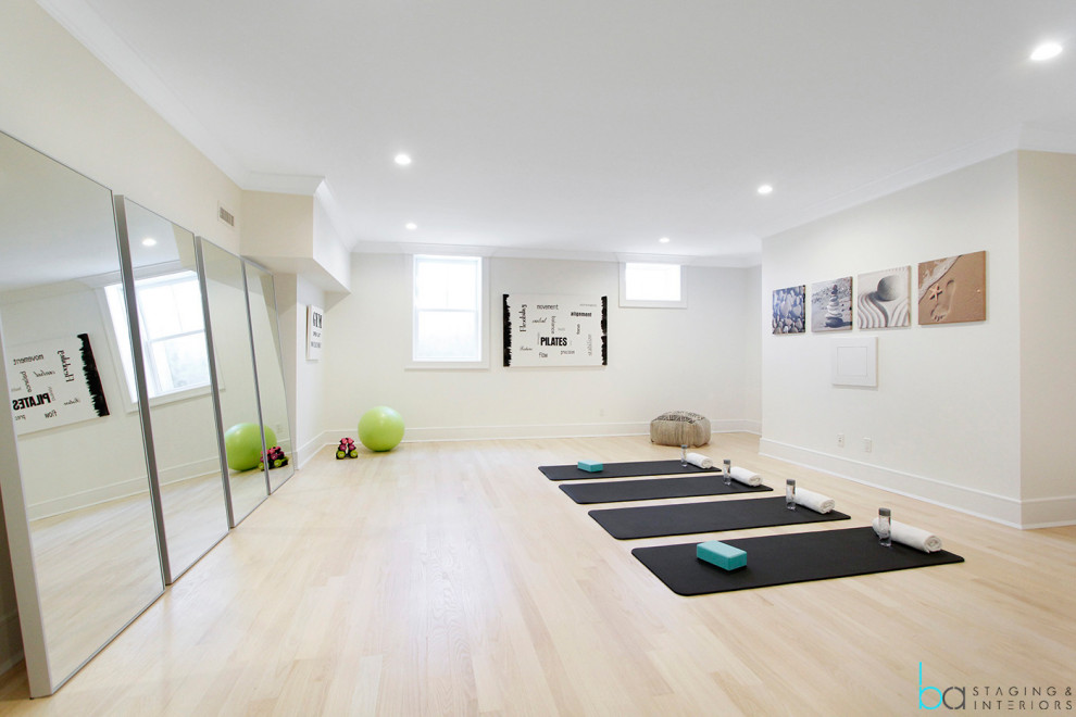 Large contemporary home yoga studio in New York with white walls, light hardwood floors and beige floor.
