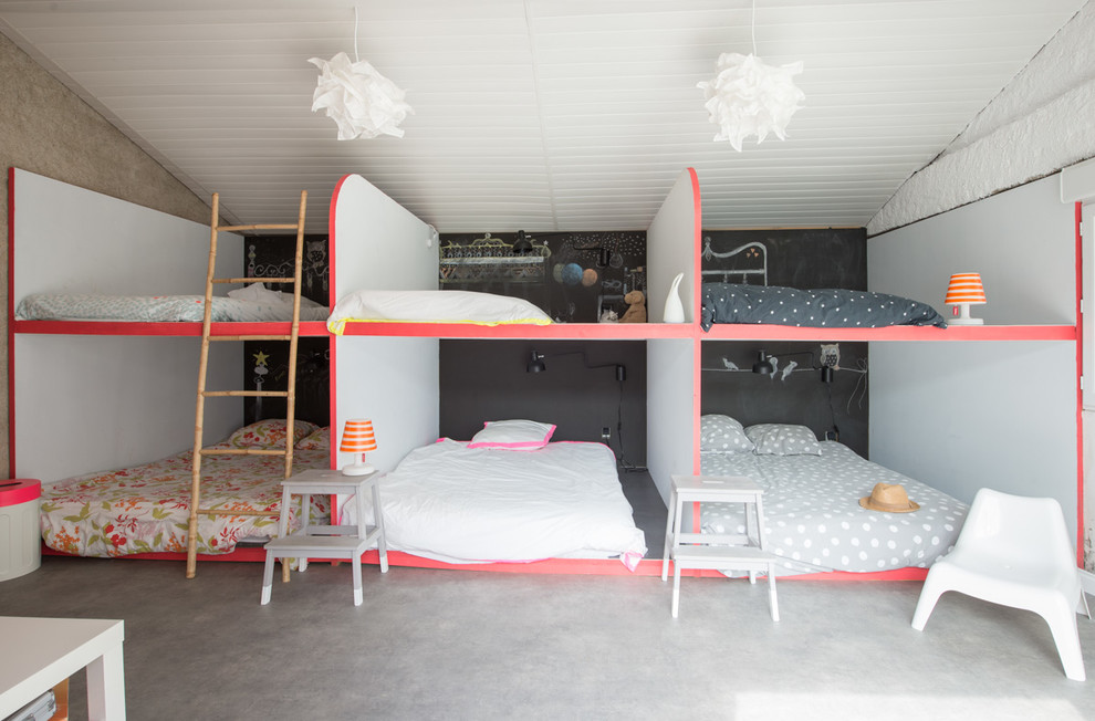 This is an example of a mid-sized contemporary gender-neutral kids' bedroom for kids 4-10 years old in Montpellier with concrete floors and multi-coloured walls.