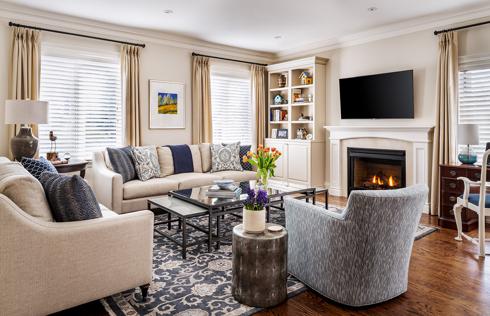 Inspiration for a mid-sized traditional open concept family room in Toronto with beige walls, medium hardwood floors, a standard fireplace, a wood fireplace surround, a wall-mounted tv and brown floor.