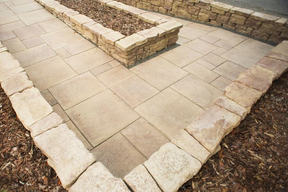 This is an example of a mid-sized traditional front yard partial sun garden for spring in Chicago with a retaining wall and natural stone pavers.