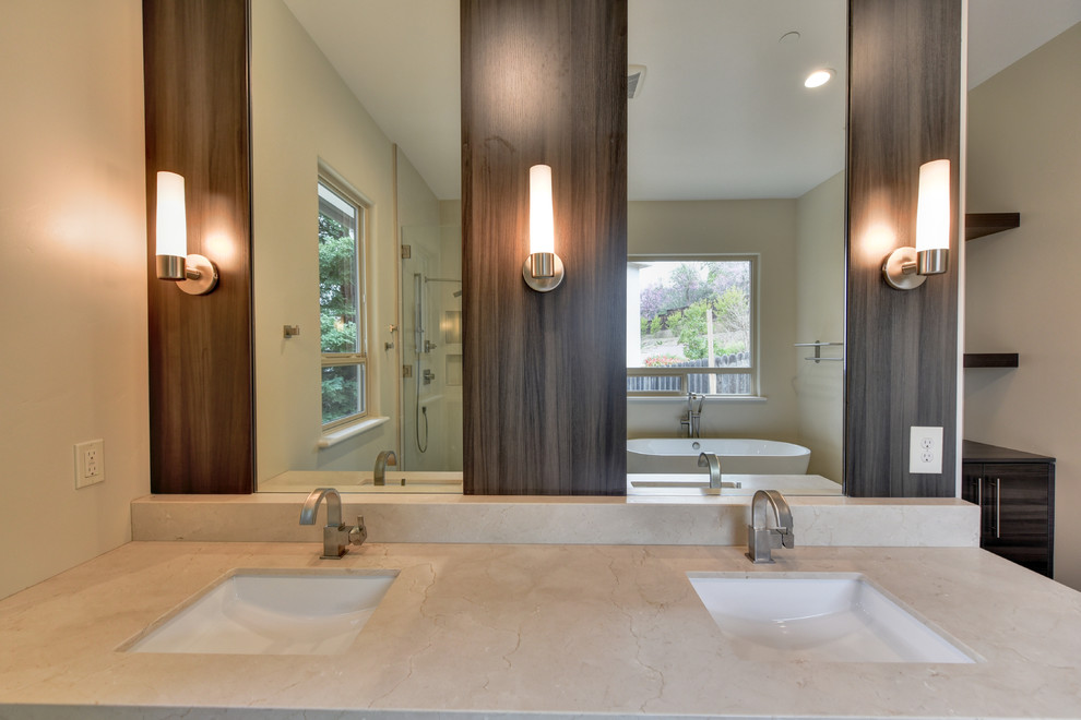 Large contemporary master bathroom in Sacramento with flat-panel cabinets, a freestanding tub, a drop-in sink, dark wood cabinets, an alcove shower, beige tile, travertine, beige walls, laminate floors, engineered quartz benchtops, beige floor, a hinged shower door and beige benchtops.