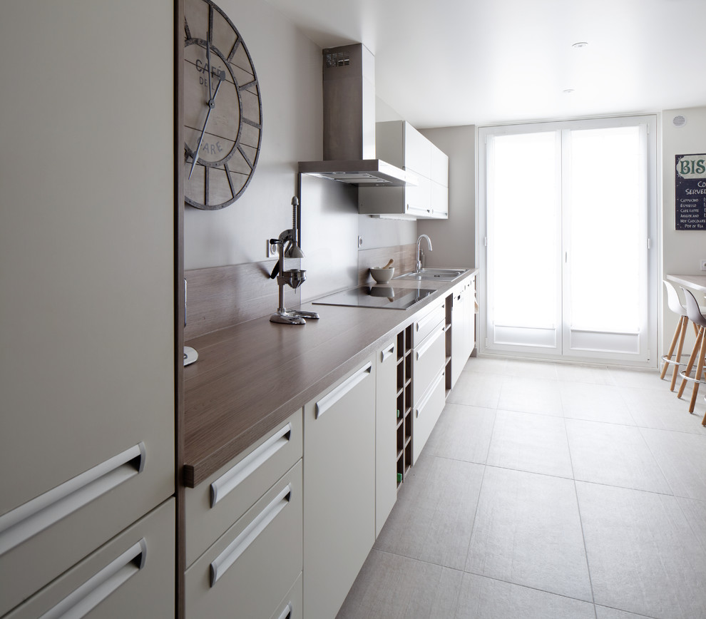 This is an example of a large contemporary galley separate kitchen in Paris with an undermount sink, flat-panel cabinets, white cabinets, laminate benchtops, panelled appliances and no island.