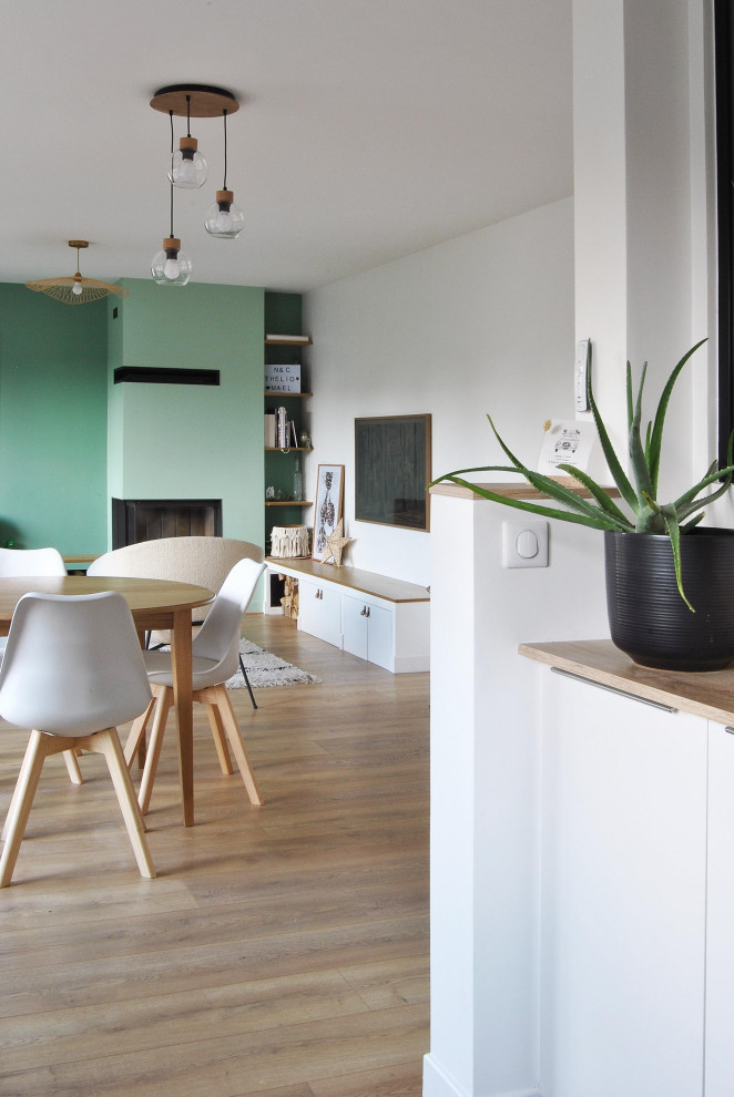 This is an example of a medium sized scandinavian open plan dining room in Paris with green walls, light hardwood flooring, a corner fireplace and a plastered fireplace surround.