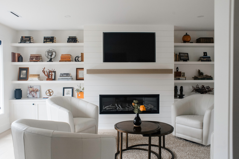 На фото: открытая гостиная комната среднего размера в стиле неоклассика (современная классика) с белыми стенами, камином и телевизором на стене с