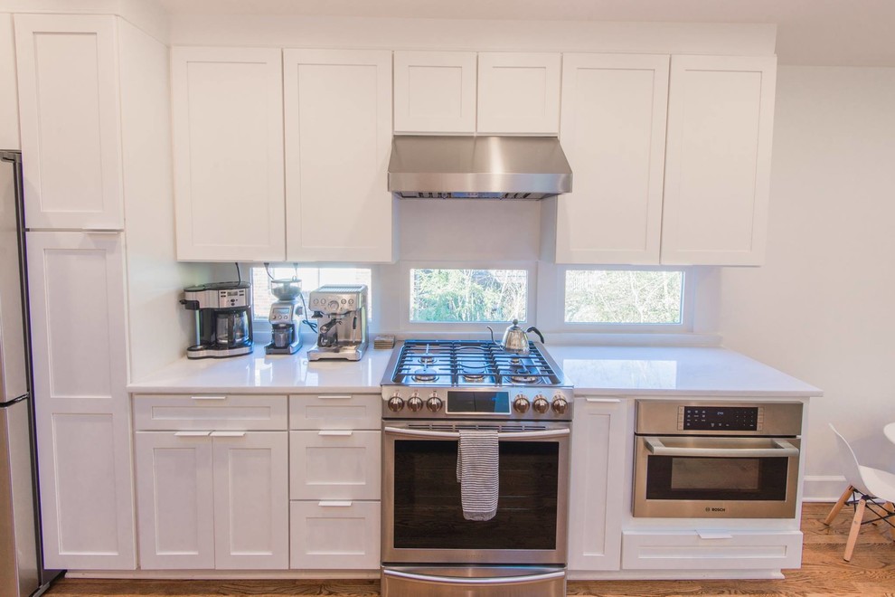 Inspiration for a mid-sized transitional single-wall light wood floor open concept kitchen remodel in Atlanta with a double-bowl sink, recessed-panel cabinets, white cabinets, marble countertops, white backsplash, subway tile backsplash, stainless steel appliances and an island