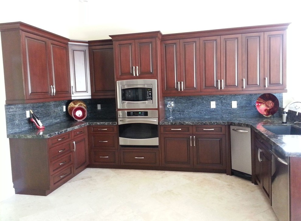 Inspiration for a large traditional u-shaped eat-in kitchen in Las Vegas with an undermount sink, raised-panel cabinets, dark wood cabinets, granite benchtops, black splashback, stone slab splashback, stainless steel appliances, ceramic floors and with island.