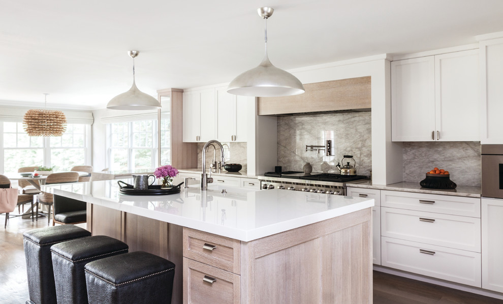 Design ideas for a transitional eat-in kitchen in New York with shaker cabinets, white cabinets, grey splashback, stainless steel appliances, with island, marble splashback, an undermount sink, white benchtop, light hardwood floors and brown floor.