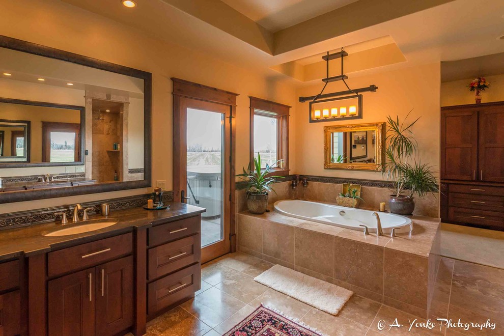 Design ideas for a large country master bathroom in Other with shaker cabinets, dark wood cabinets, a drop-in tub, a corner shower, beige tile, brown tile, ceramic tile, beige walls, travertine floors, an undermount sink and soapstone benchtops.