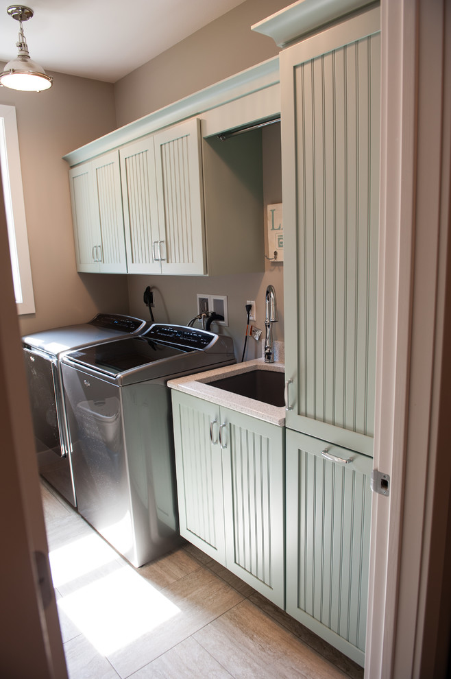 This is an example of a mid-sized transitional single-wall dedicated laundry room in Other with an undermount sink, shaker cabinets, blue cabinets, quartz benchtops, brown walls, porcelain floors, a side-by-side washer and dryer, beige floor and grey benchtop.