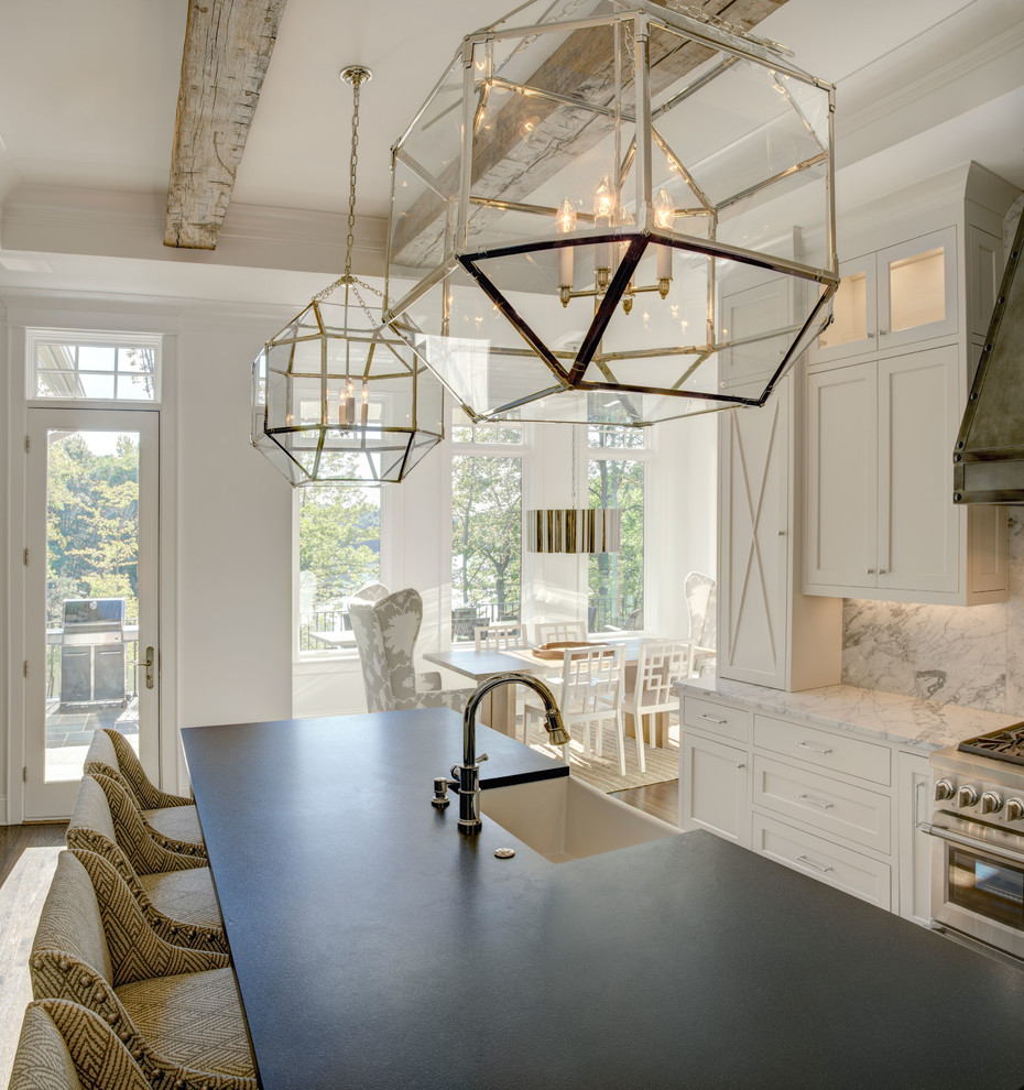 Inspiration for an expansive country l-shaped eat-in kitchen in Charlotte with an undermount sink, shaker cabinets, white cabinets, marble benchtops, white splashback, stone slab splashback, stainless steel appliances, medium hardwood floors, with island, brown floor and grey benchtop.