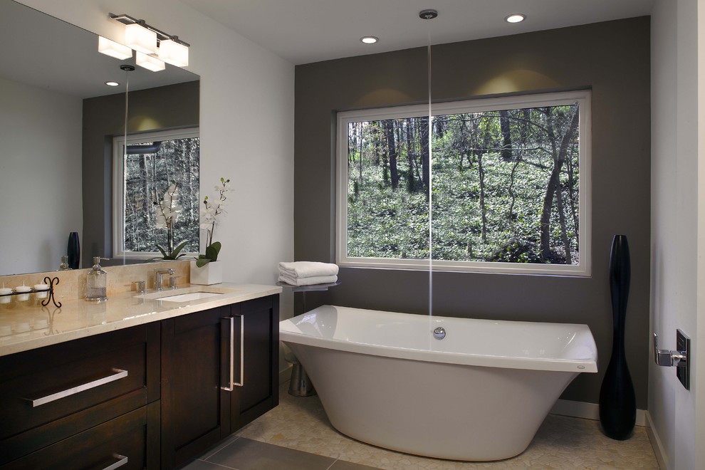 Photo of a modern bathroom in Atlanta with an undermount sink, shaker cabinets, dark wood cabinets, a freestanding tub and beige tile.