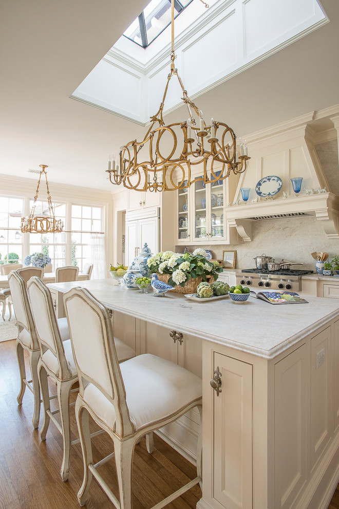 Large traditional l-shaped open plan kitchen in Dallas with shaker cabinets, white cabinets, marble benchtops, white splashback, medium hardwood floors, with island, an undermount sink, panelled appliances, marble splashback and brown floor.