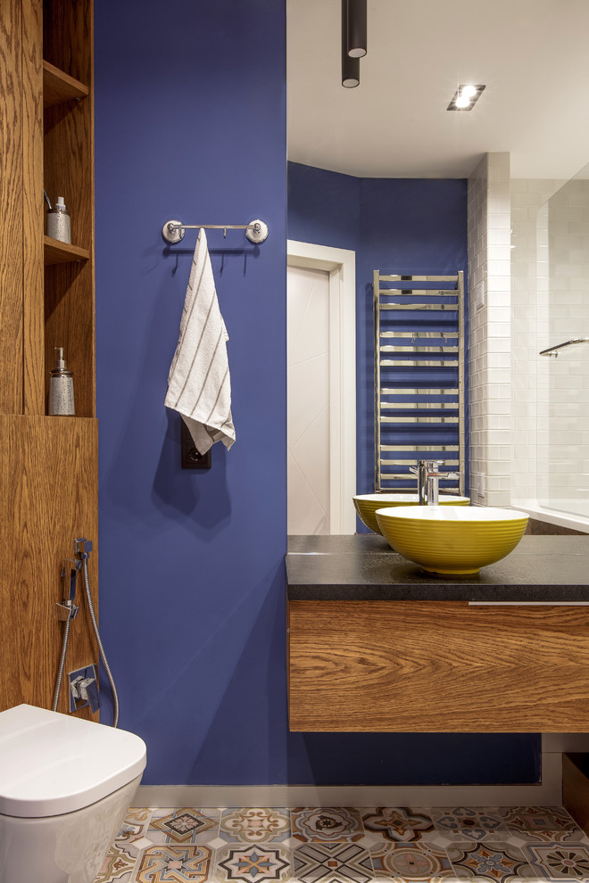 This is an example of a contemporary bathroom in Other with flat-panel cabinets, medium wood cabinets, purple walls, multi-coloured floor and black benchtops.
