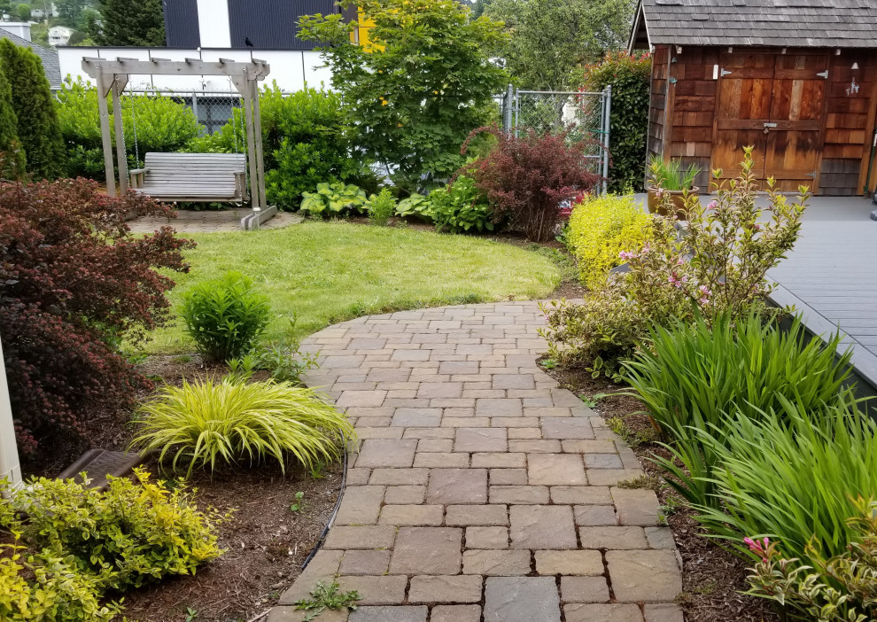 This is an example of a small rustic full sun backyard concrete paver landscaping in Seattle.