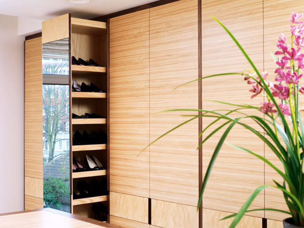 Design ideas for a large modern gender-neutral walk-in wardrobe in London with flat-panel cabinets, carpet and light wood cabinets.