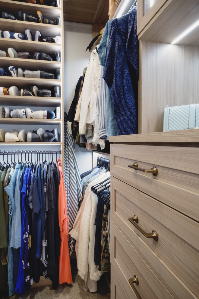 Photo of a mid-sized transitional gender-neutral walk-in wardrobe in Minneapolis with shaker cabinets, medium wood cabinets, carpet and beige floor.