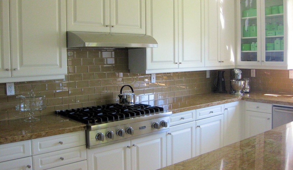 Kitchen - transitional medium tone wood floor kitchen idea with raised-panel cabinets, white cabinets, solid surface countertops, green backsplash, glass tile backsplash and stainless steel appliances