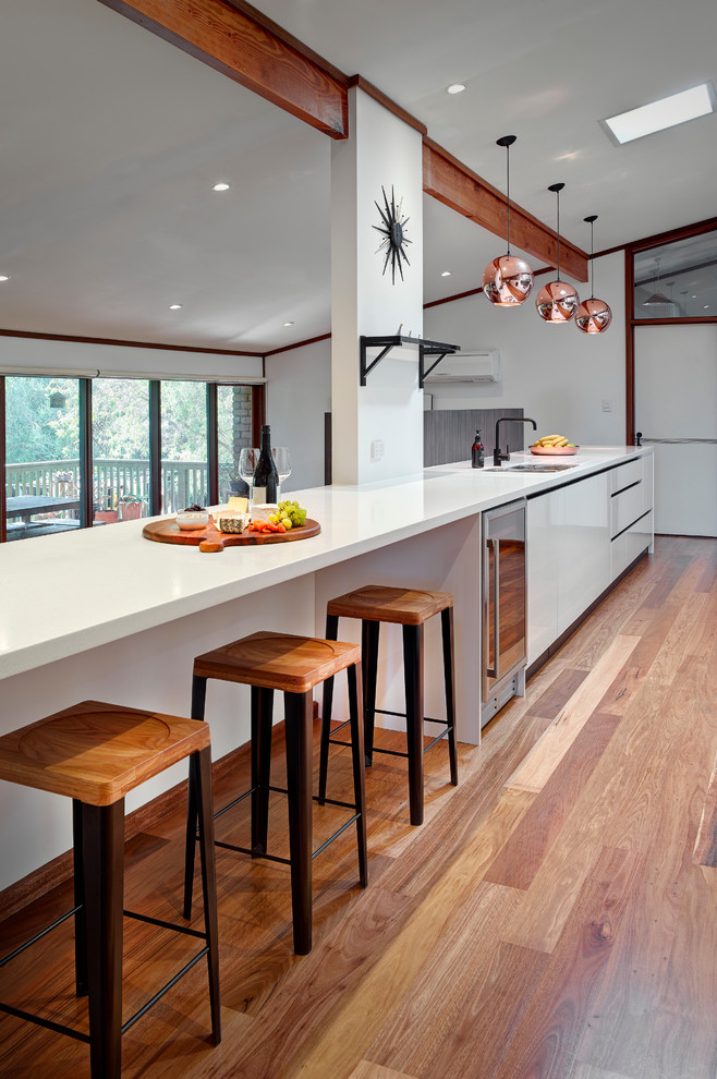 Design ideas for a large contemporary galley open plan kitchen in Other with a double-bowl sink, white cabinets, laminate benchtops, glass sheet splashback, stainless steel appliances and medium hardwood floors.