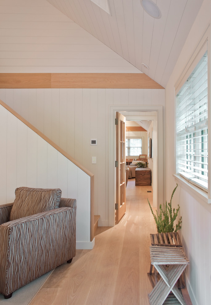 This is an example of a contemporary hallway in Boston with white walls and medium hardwood floors.