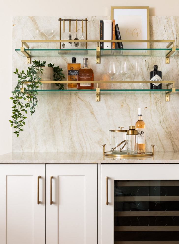 Inspiration for a mid-sized transitional single-wall home bar in Calgary with shaker cabinets, white cabinets, quartz benchtops, beige splashback, engineered quartz splashback, dark hardwood floors, brown floor and beige benchtop.