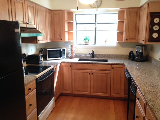 Enclosed kitchen - small transitional u-shaped medium tone wood floor enclosed kitchen idea with an undermount sink, raised-panel cabinets, medium tone wood cabinets, granite countertops, black appliances and no island