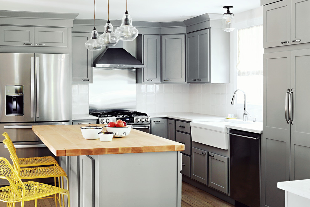 Inspiration for a mid-sized transitional l-shaped eat-in kitchen in Portland Maine with a farmhouse sink, shaker cabinets, grey cabinets, white splashback, porcelain splashback, stainless steel appliances, medium hardwood floors, with island and brown floor.