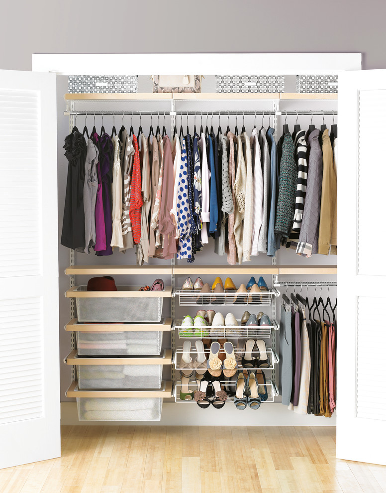 Photo of a large modern gender-neutral built-in wardrobe in Other with light hardwood floors.