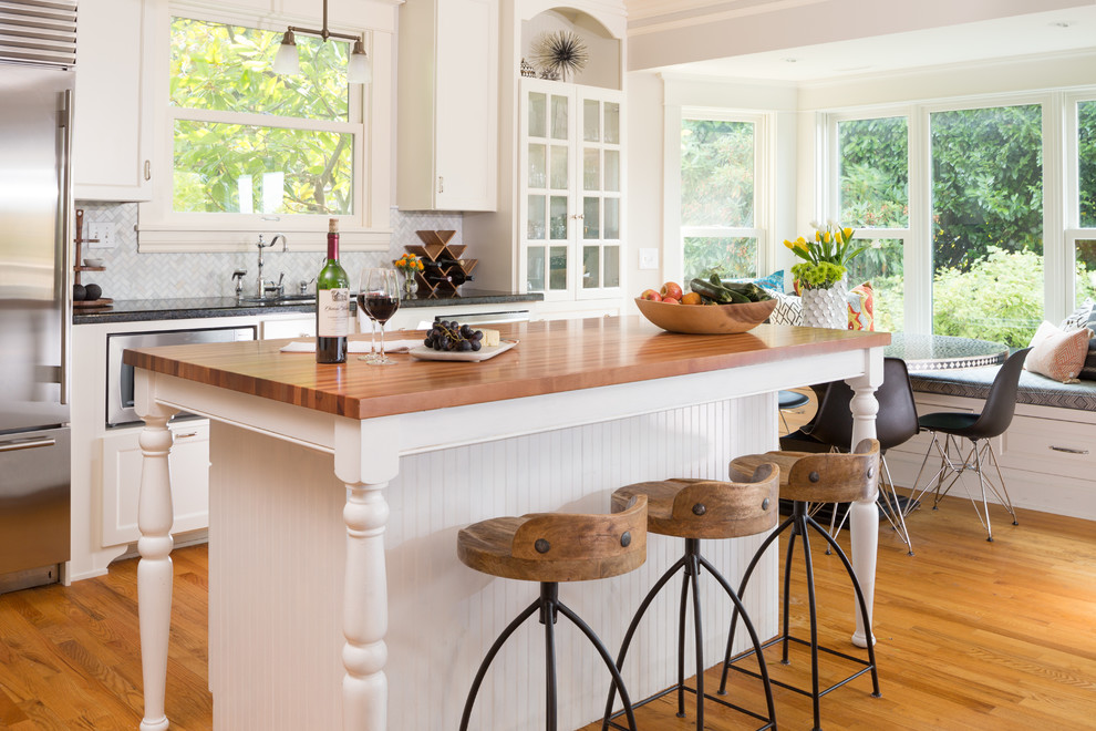 Inspiration for a large l-shaped light wood floor open concept kitchen remodel in Seattle with flat-panel cabinets, white cabinets, wood countertops, gray backsplash, stainless steel appliances and an island