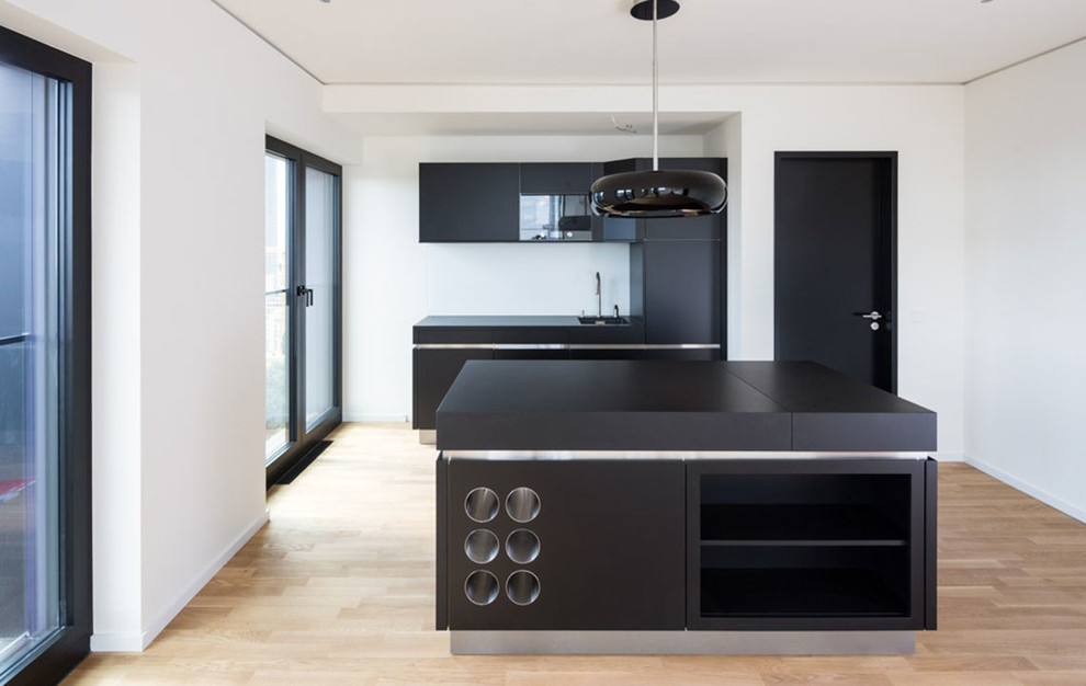 Inspiration for a mid-sized contemporary separate kitchen in Frankfurt with a single-bowl sink, flat-panel cabinets, light hardwood floors, with island and white splashback.