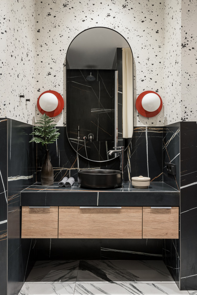Photo of a mid-sized modern 3/4 bathroom in Other with flat-panel cabinets, an alcove shower, a wall-mount toilet, black tile, porcelain tile, porcelain floors, a drop-in sink, tile benchtops, white floor, a hinged shower door, black benchtops, a single vanity, a floating vanity and wallpaper.