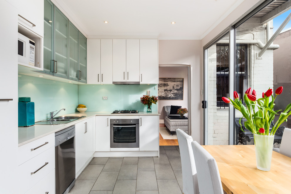 This is an example of a contemporary l-shaped eat-in kitchen in Sydney with a double-bowl sink, flat-panel cabinets, white cabinets, stainless steel appliances and no island.