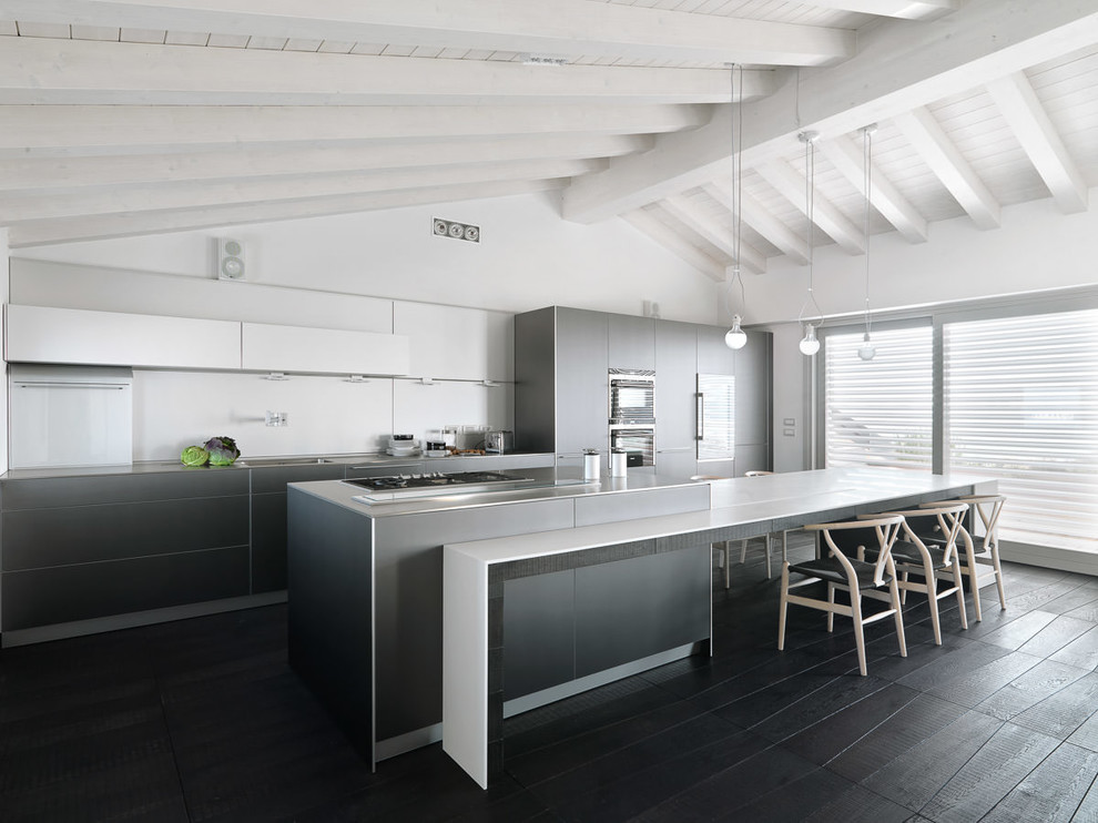 Inspiration for an expansive contemporary kitchen in Milan with a drop-in sink, flat-panel cabinets, grey cabinets, stainless steel benchtops, white splashback, stainless steel appliances and dark hardwood floors.