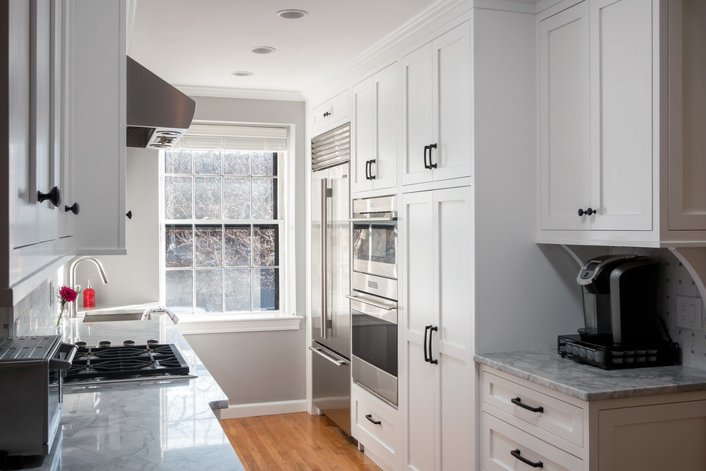 This is an example of a mid-sized transitional galley eat-in kitchen in Boston with an undermount sink, shaker cabinets, white cabinets, quartzite benchtops, white splashback, marble splashback, stainless steel appliances and medium hardwood floors.