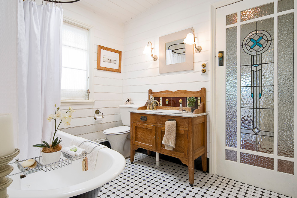 Photo of a beach style bathroom in Sydney with shaker cabinets, medium wood cabinets, a freestanding tub, a shower/bathtub combo, white walls, mosaic tile floors, a drop-in sink, multi-coloured floor, a shower curtain, white benchtops, a single vanity, a freestanding vanity and planked wall panelling.