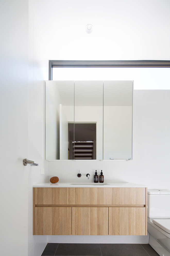 Photo of a mid-sized contemporary 3/4 bathroom in Sydney with flat-panel cabinets, medium wood cabinets, an open shower, a one-piece toilet, white tile, ceramic tile, white walls, ceramic floors, an undermount sink, engineered quartz benchtops, beige floor and an open shower.