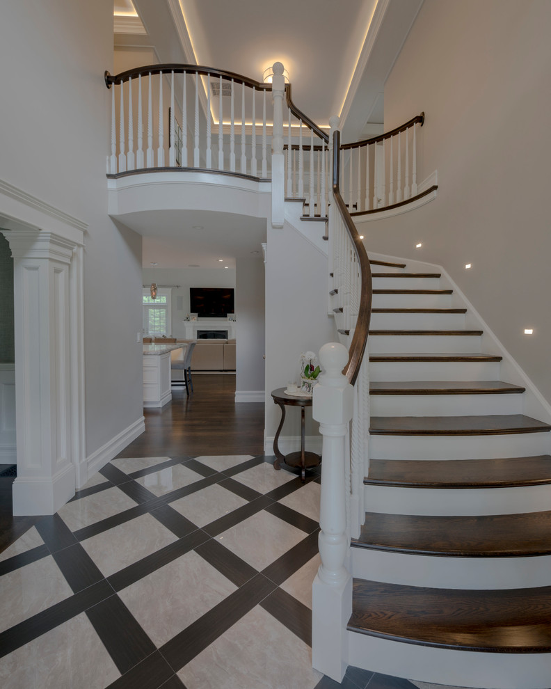 Large modern wood curved staircase in Boston with painted wood risers and wood railing.
