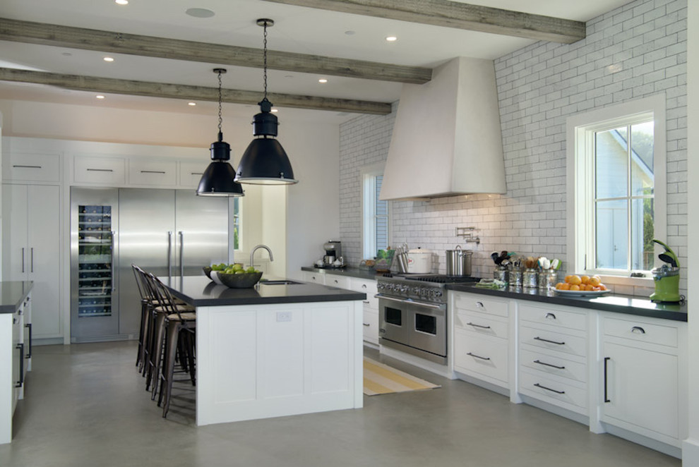 This is an example of a large country galley eat-in kitchen in San Francisco with white cabinets, stainless steel appliances, concrete floors, an undermount sink, flat-panel cabinets, quartz benchtops, grey splashback, subway tile splashback, with island and grey floor.