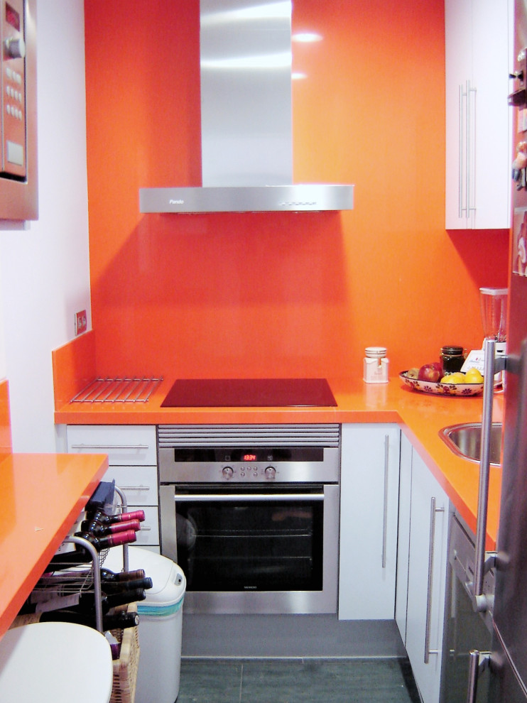 バルセロナにあるラグジュアリーな小さなモダンスタイルのおしゃれなキッチン (シングルシンク、白いキャビネット、クオーツストーンカウンター、オレンジのキッチンパネル、クオーツストーンのキッチンパネル、シルバーの調理設備、スレートの床、グレーの床、オレンジのキッチンカウンター) の写真