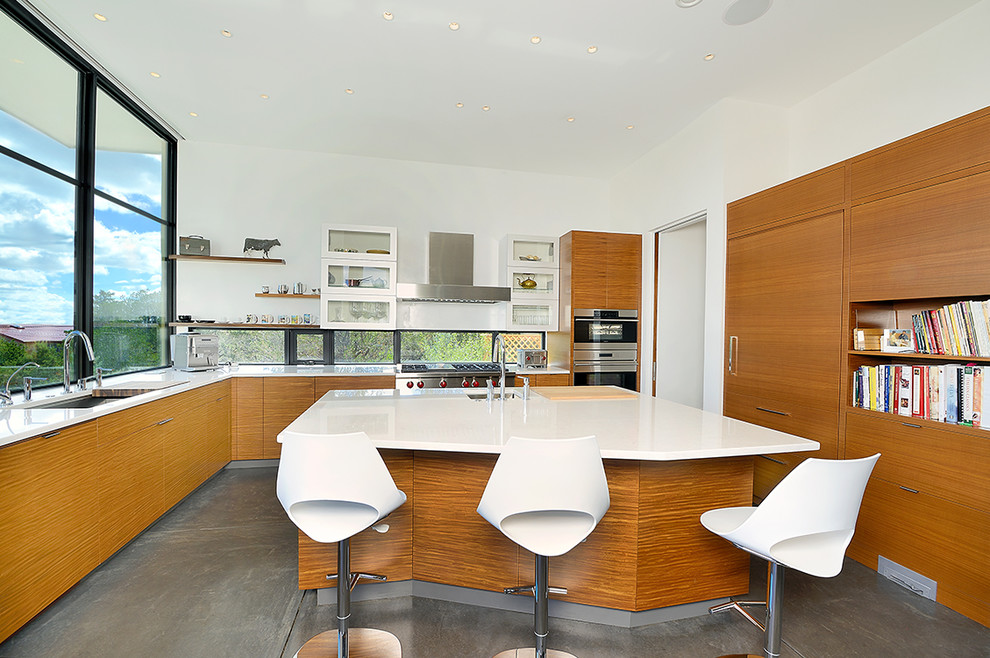 Large modern u-shaped open plan kitchen in Other with an undermount sink, flat-panel cabinets, medium wood cabinets, quartz benchtops, brown splashback, window splashback, stainless steel appliances, concrete floors, with island and brown floor.