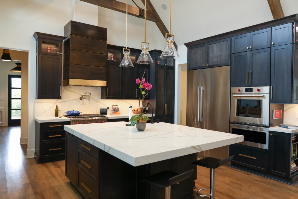 Open concept kitchen - large transitional u-shaped light wood floor open concept kitchen idea with a farmhouse sink, flat-panel cabinets, dark wood cabinets, quartz countertops, white backsplash, quartz backsplash, stainless steel appliances, an island and white countertops