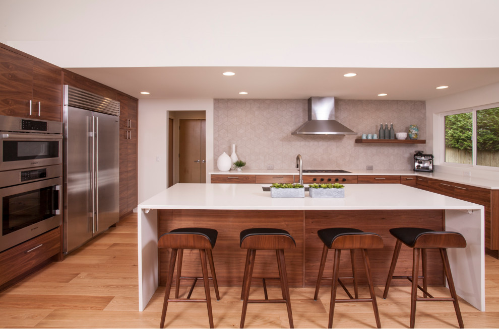 This is an example of a large midcentury u-shaped open plan kitchen in Seattle with an integrated sink, flat-panel cabinets, dark wood cabinets, quartzite benchtops, grey splashback, porcelain splashback, stainless steel appliances, medium hardwood floors, with island, brown floor and white benchtop.