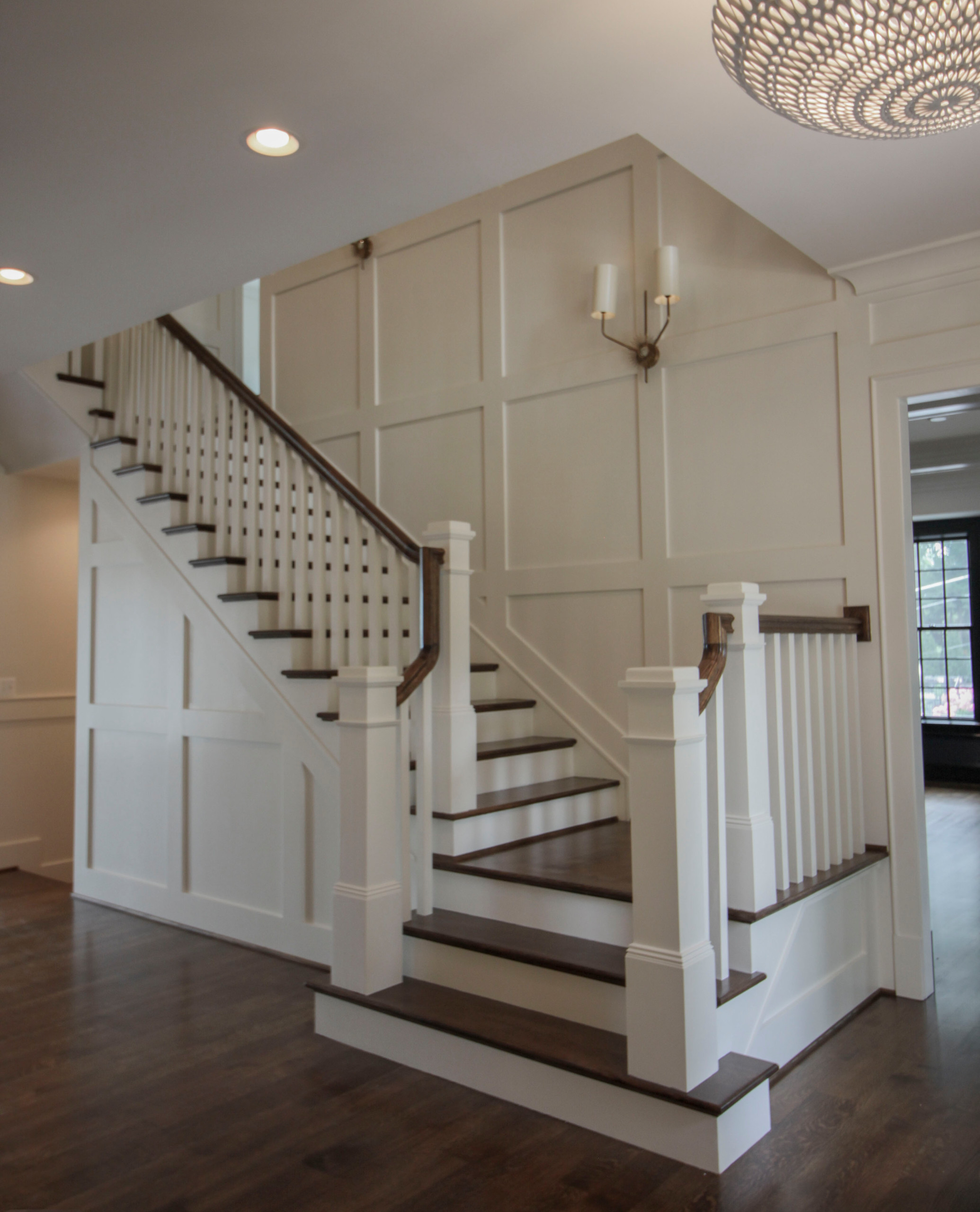The combination of dark-stained treads and handrails with white-painted vertical balusters and newels, tie the stairs in with the other wonderful architectural elements of this new and elegant home. T