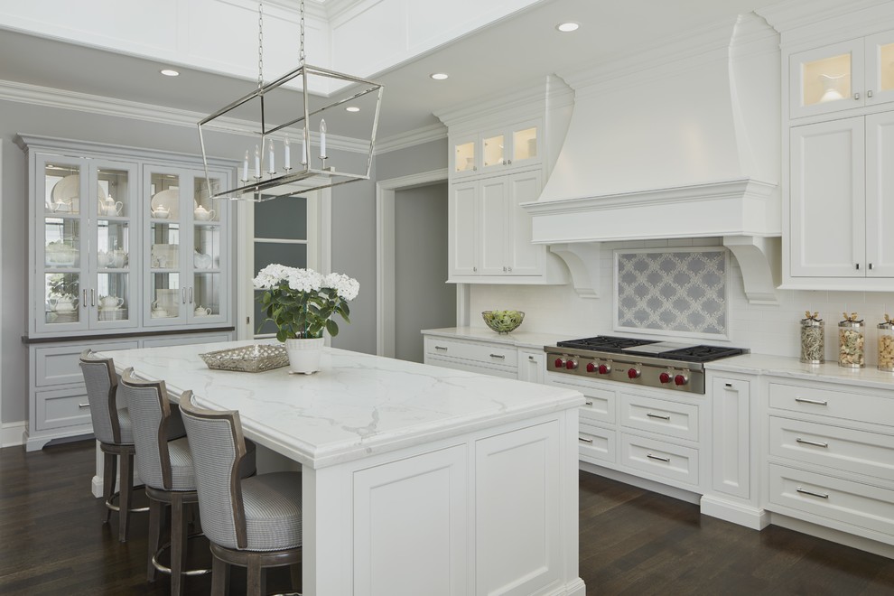 Inspiration for a transitional kitchen in Chicago with white cabinets, quartz benchtops, beaded inset cabinets, white splashback, subway tile splashback, stainless steel appliances, dark hardwood floors, with island, brown floor and white benchtop.