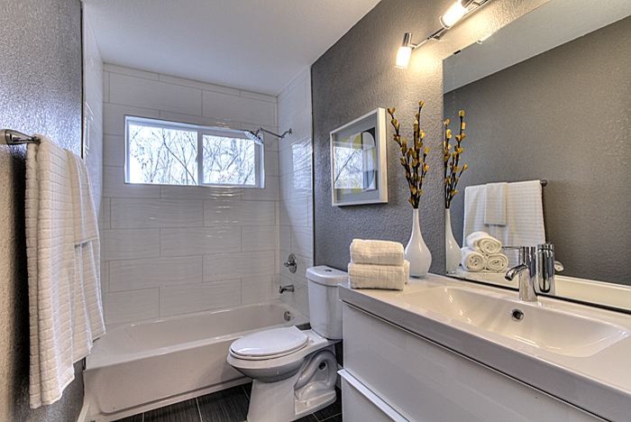 Mid-sized transitional alcove bathtub photo with white cabinets, a one-piece toilet, gray walls and an integrated sink
